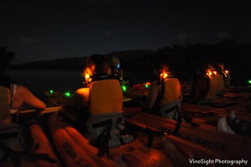 A group of people with night lights in orange kayaks experiencing the dusk on the Laguna Grande